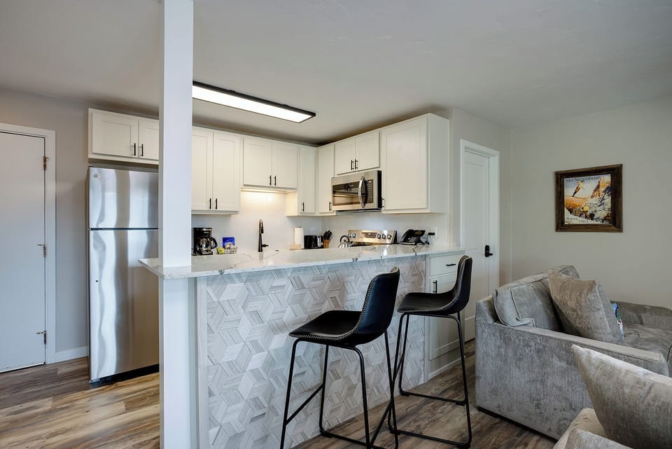 Your modern kitchen features white cabinets, stainless steel appliances, and a breakfast bar where you can enjoy morning coffee together.