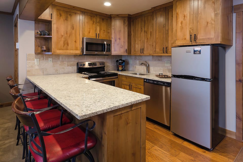 Your fully equipped kitchen features warm wood cabinetry, granite countertops, and stainless steel appliances, creating the perfect space for preparing meals during your stay.