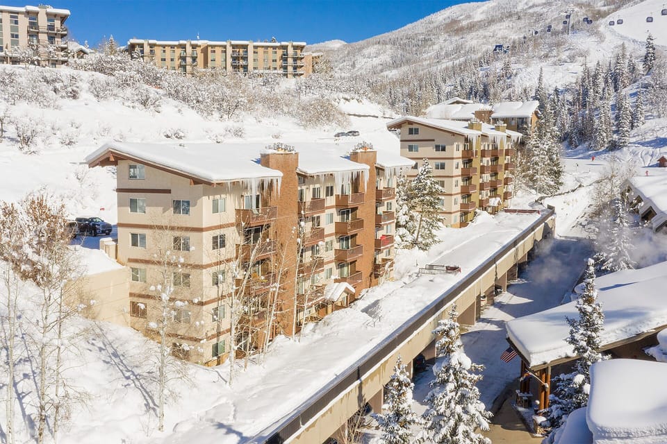 Snow-covered mountain resort buildings nestled in pristine winter valley with ski slopes nearby.