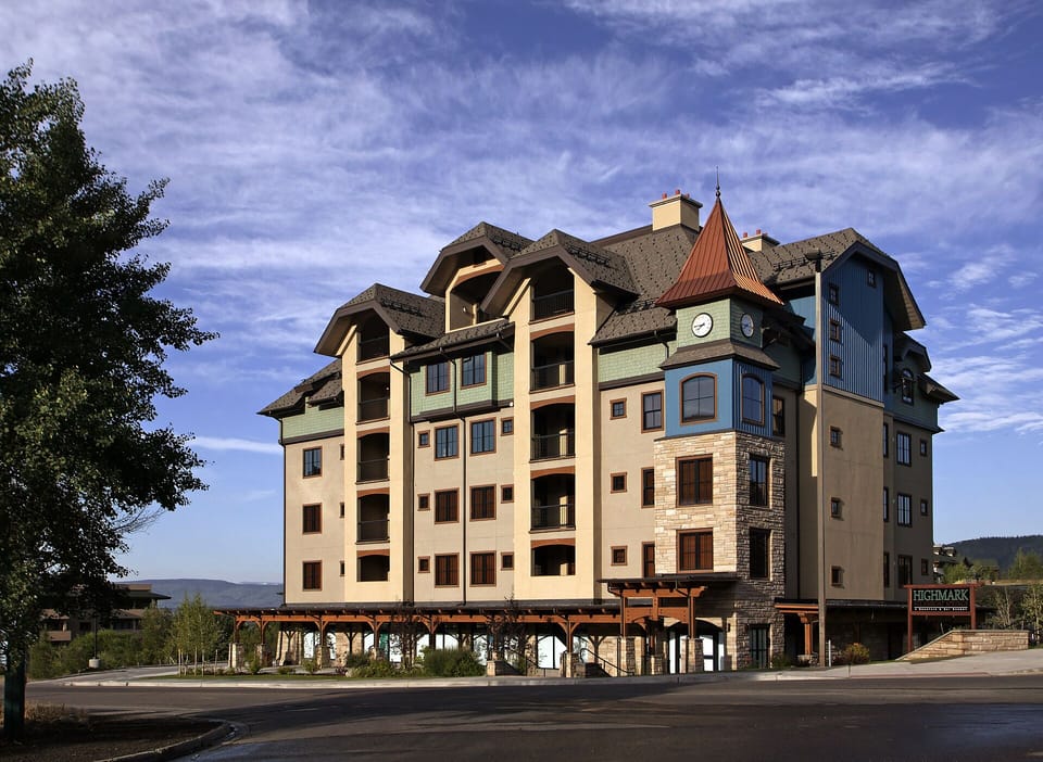 Elegant mountain resort building with distinctive tower and stunning architecture, nestled in a scenic valley setting.