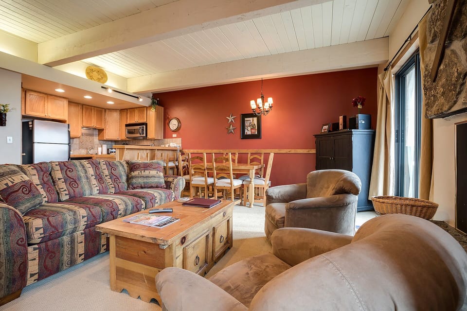 Unwind in this spacious open living area where rustic charm meets comfort—plush seating, stone fireplace, and mountain lodge atmosphere.