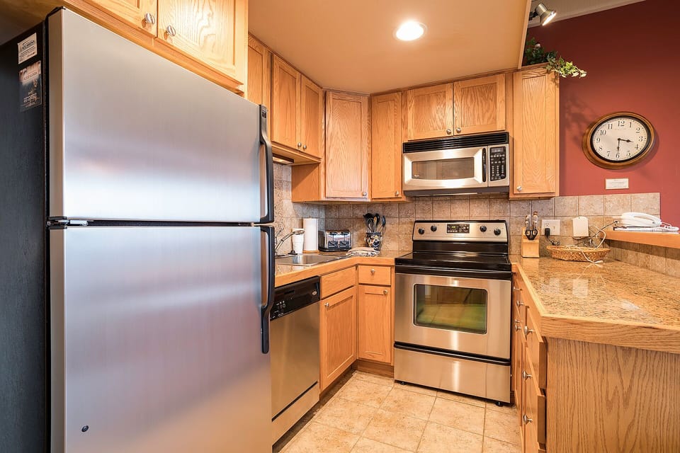 Your fully equipped kitchen features stainless steel appliances, granite countertops, and warm wood cabinets—perfect for preparing meals during your stay.