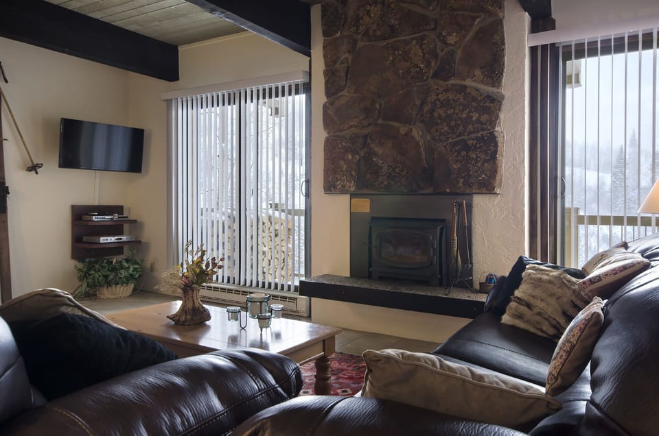 Sink into plush leather sofas beside a striking stone fireplace, where natural light streams through tall windows and your favorite shows await on the flat-screen TV.