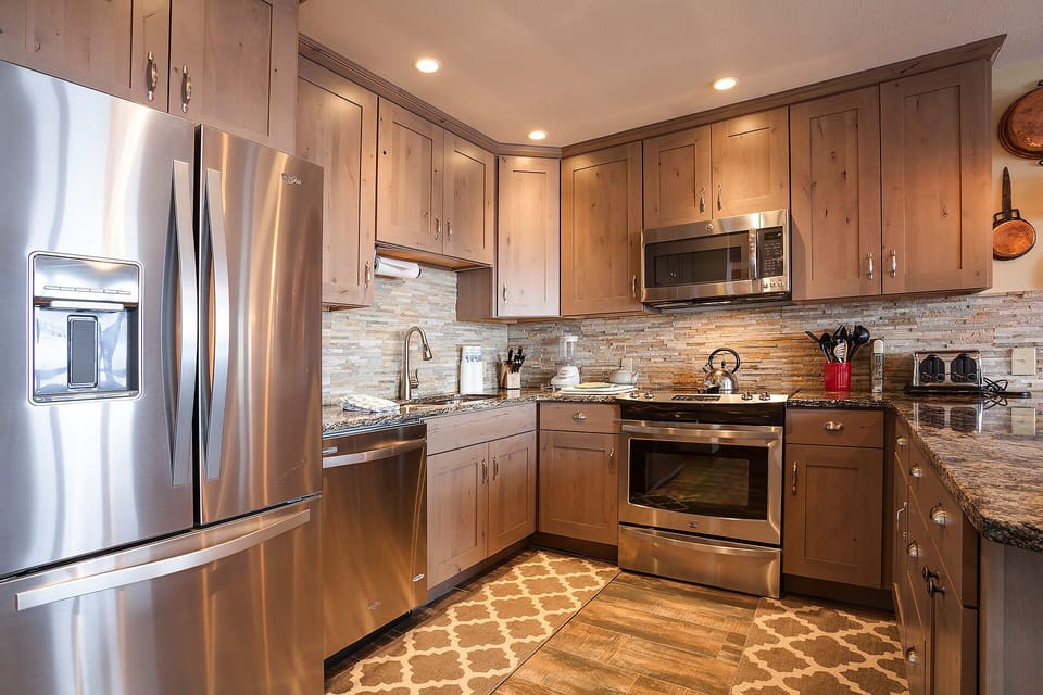 Cook your favorite meals in this fully-equipped kitchen featuring stainless steel appliances, granite counters, and warm wood cabinets.