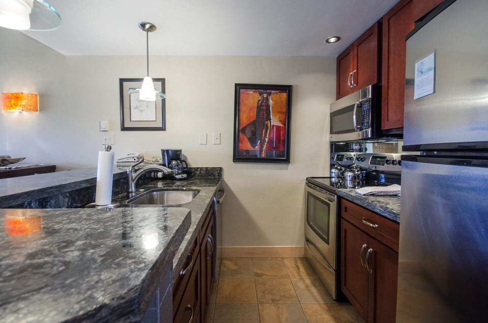 Your fully equipped kitchen features sleek granite countertops, stainless steel appliances, and rich cherry cabinets—perfect for preparing meals during your stay.