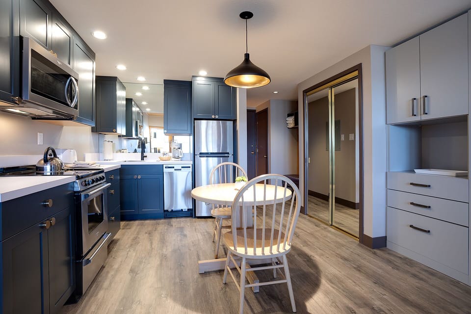 Your modern kitchen awaits with sleek blue cabinets, stainless steel appliances, and a cozy breakfast nook for morning coffee.