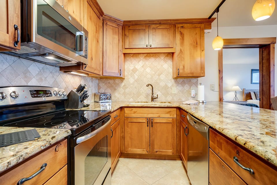 Your fully equipped kitchen features warm wood cabinetry, granite countertops, and modern appliances—perfect for preparing memorable meals during your stay.