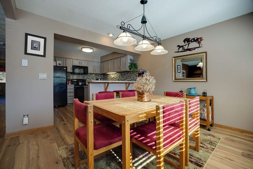 Gather around your warm dining table where memorable conversations flow beneath elegant lighting and mountain decor.