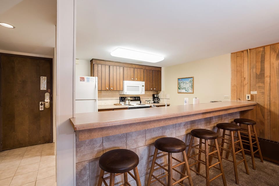 Your open kitchen with warm wood cabinets and breakfast bar seating creates the perfect space for morning coffee and casual meals.