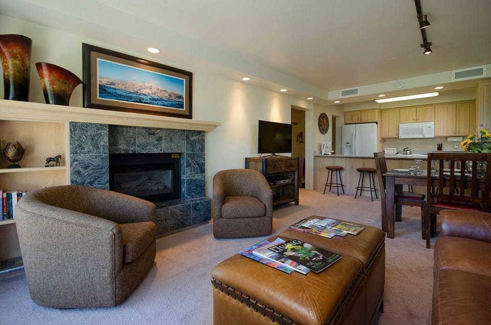 Unwind in your spacious living room with a cozy fireplace, comfortable seating, and an open kitchen perfect for creating memorable meals together.
