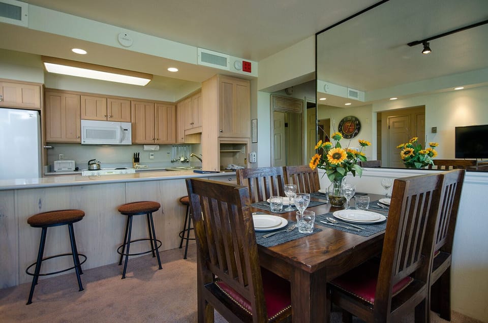 Your open-concept kitchen flows seamlessly to the dining area, where sunflowers brighten family meals around the handcrafted wooden table.