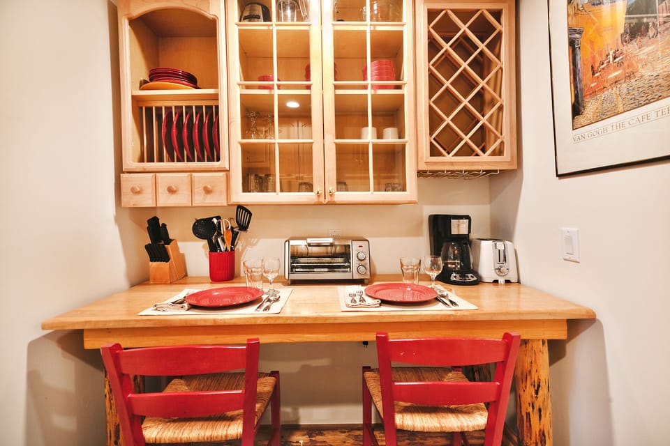Cozy dining nook in the kitchen area with red accent dishes and barstools