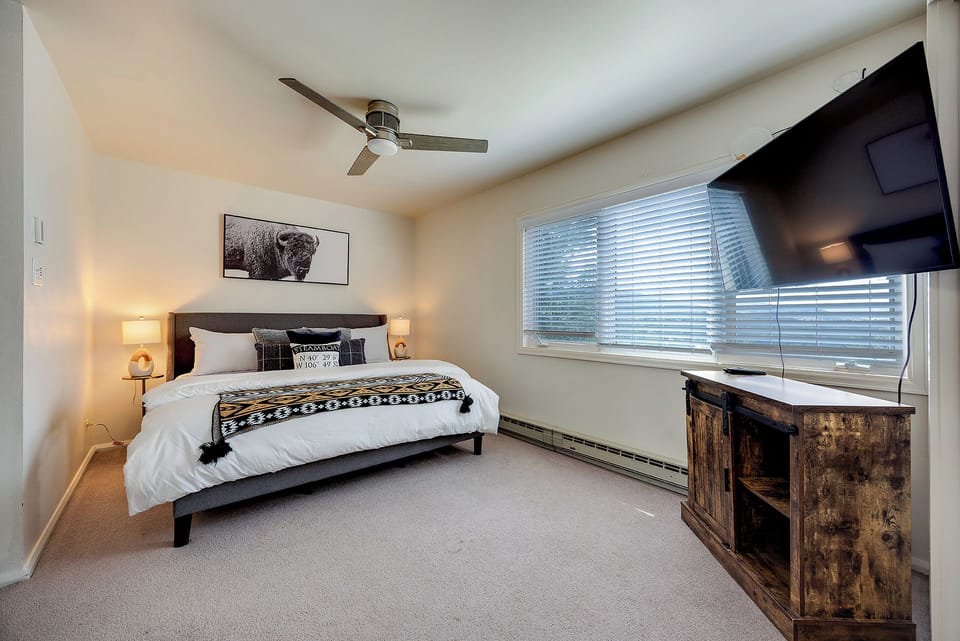 Slip into this cozy bedroom with rustic touches and modern comfort—crisp linens, soft lighting, and a ceiling fan await your restful mountain escape.