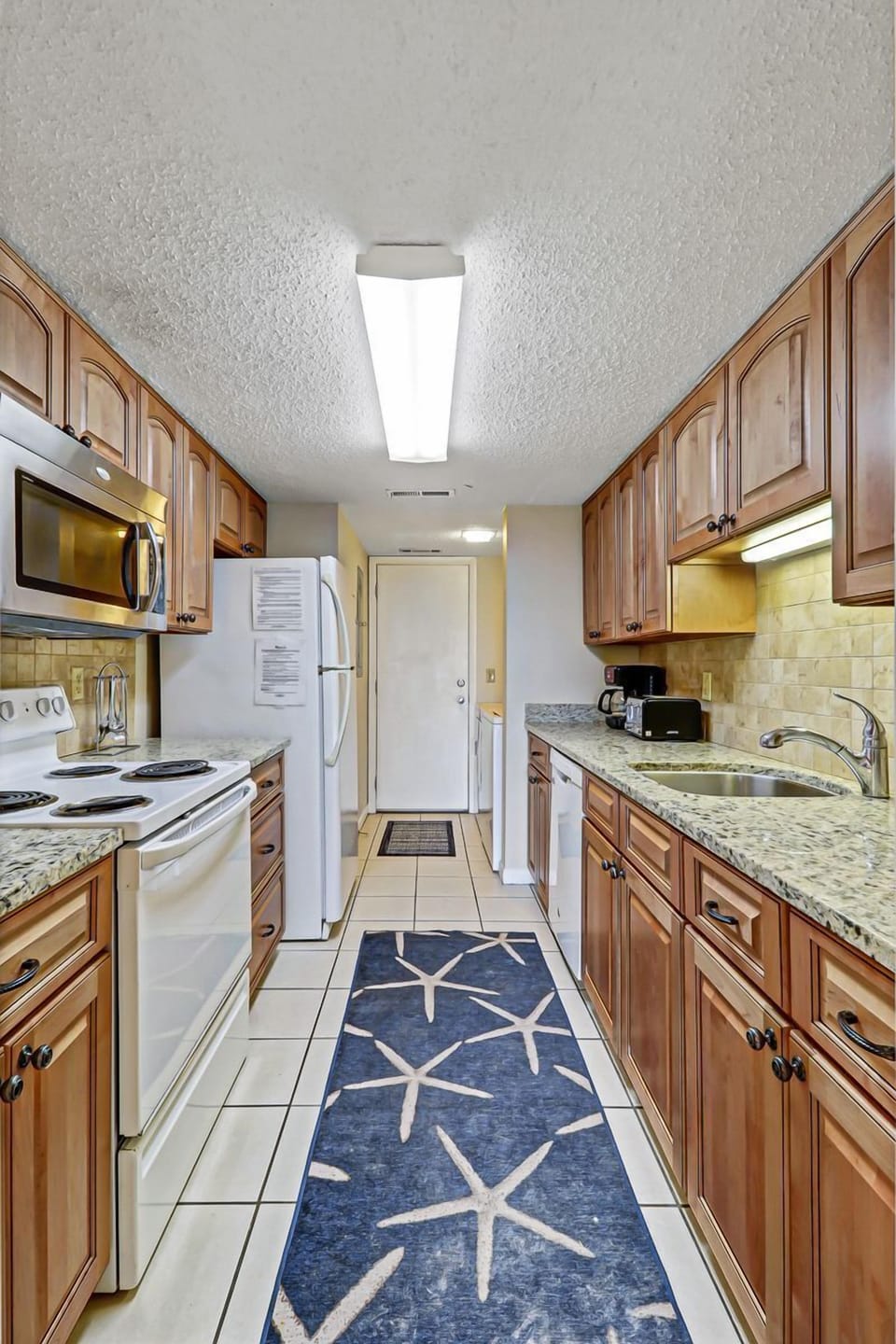 Kitchen - Plenty of work space to make memorable meals in this galley style kitchen.  Laundry room is located at the end of the room.