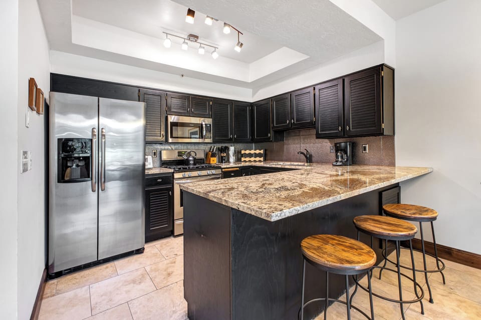 Queen Esther 2425's open kitchen concept with breakfast bar with 3 barstools separating the dining area.