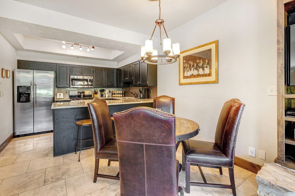 Queen Esther 2425's dining area with seating for 4 on leather chairs and a round table.
