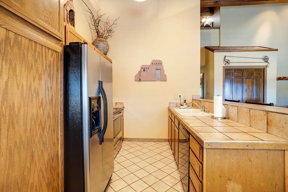 Your spacious kitchen features warm wood cabinets, tiled counters, and modern appliances, creating the perfect space for preparing memorable meals.