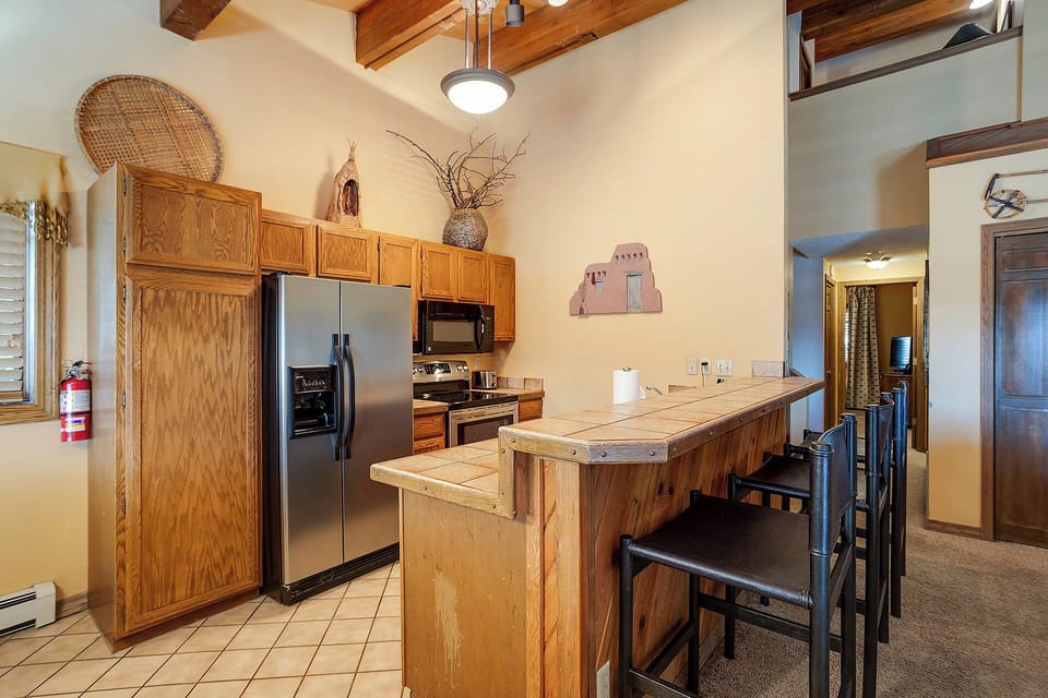 Your fully-equipped kitchen welcomes you with warm wood cabinetry and a spacious island perfect for preparing meals together.