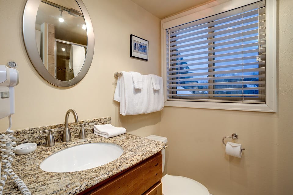 Freshen up in your private bathroom featuring a granite vanity, modern fixtures, and soft towels—everything you need for a comfortable stay.
