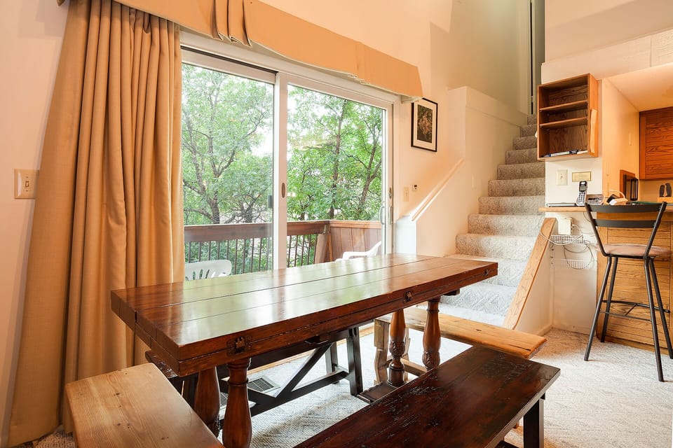 Gather around your rustic dining table for memorable meals while gazing at peaceful treetops through the sliding glass door.