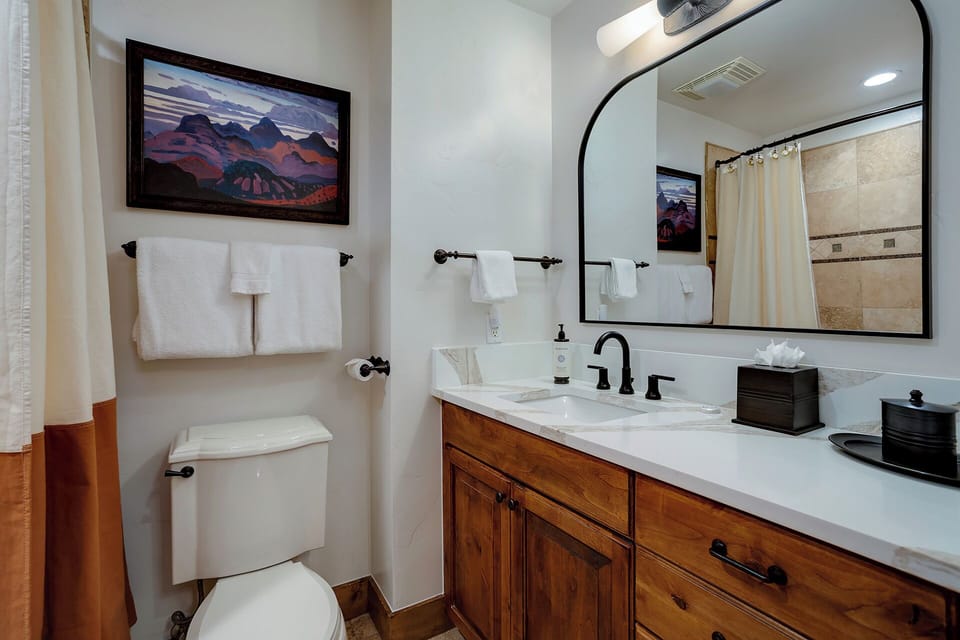 Step into your beautifully appointed bathroom with warm wood vanity, elegant marble countertops, and crisp white towels ready for you. Enjoy the cozy mountain artwork and thoughtful touches that make this space feel like home.