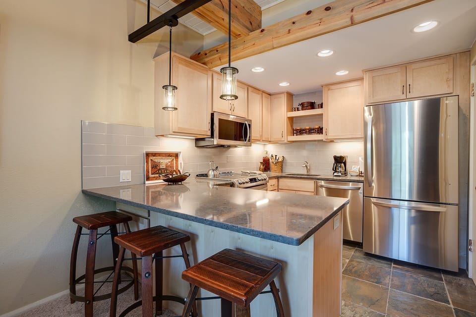 Your spacious kitchen invites culinary adventures with granite counters, stainless appliances, and rustic charm under exposed beams.