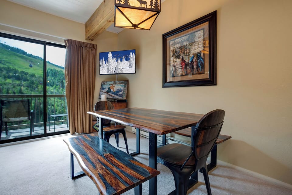 Gather around this rustic dining table where meals become memories, with mountain views framing your conversations through floor-to-ceiling windows.