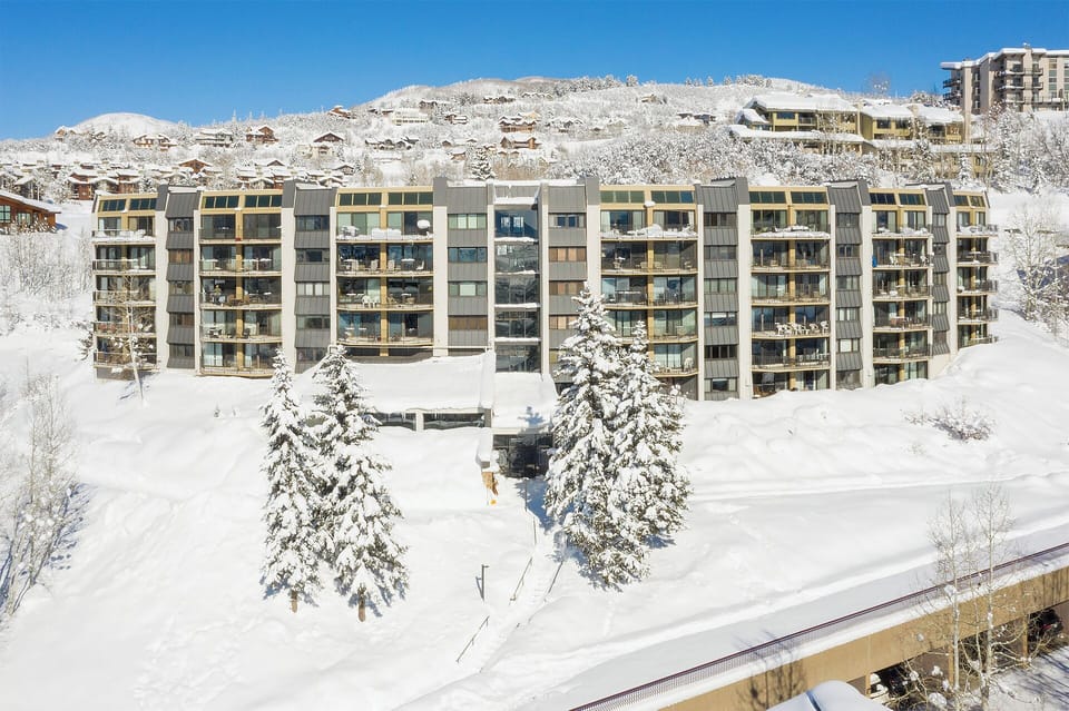Multi-level alpine property nestled in a pristine snow-covered valley, surrounded by evergreen trees and mountain views ideal for winter getaways.