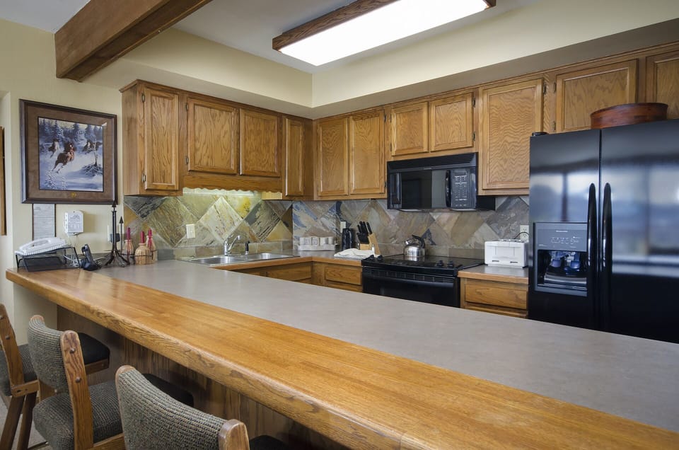 Your fully equipped kitchen features rich oak cabinetry, stainless steel appliances, and a breakfast bar where you can enjoy morning coffee with mountain views streaming through the skylight.