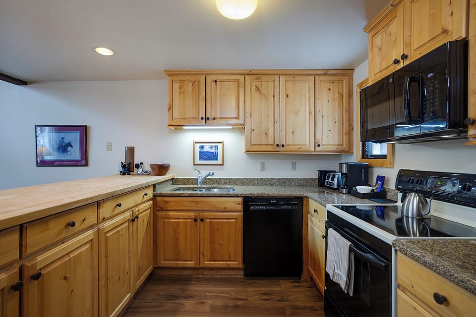 Your fully equipped kitchen features warm wood cabinets, granite counters, and modern appliances for preparing memorable meals during your stay.