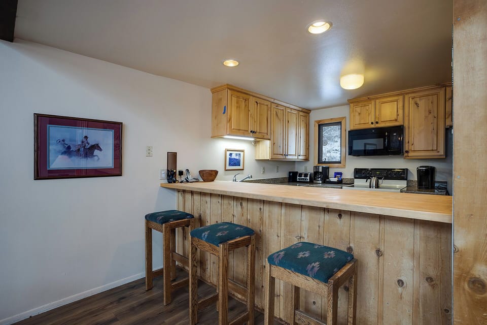 Your rustic mountain kitchen features warm wood cabinets and a breakfast bar perfect for morning coffee conversations.