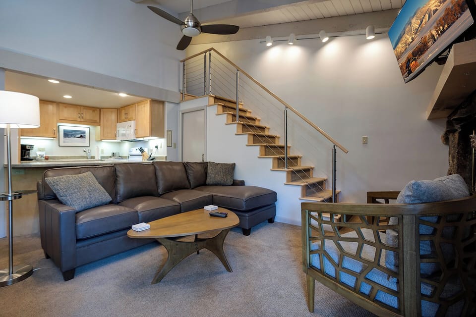 Relax in your stylish living room featuring a comfortable sectional sofa and modern staircase leading to your private loft space above.
