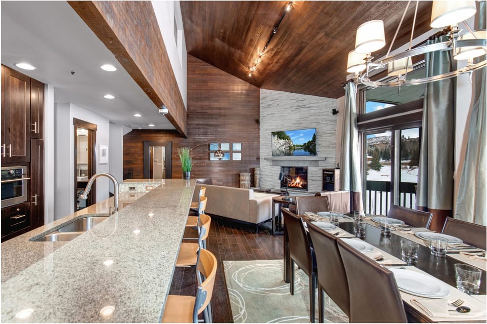 The open concept living room, dining and kitchen area with roaring fire and TV.