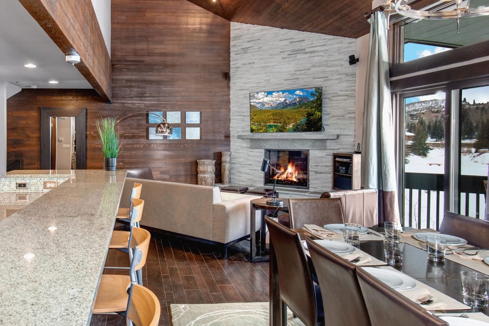The open concept living room, dining and kitchen area with roaring fire and TV.