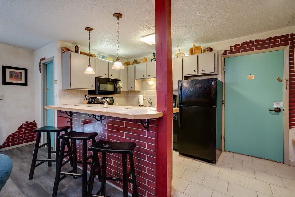 Your fully equipped kitchen features charming exposed brick, pendant lighting, and a breakfast bar where you can enjoy morning coffee.
