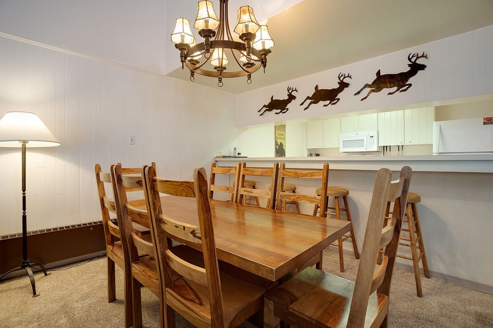 Gather around your spacious dining table for memorable meals with loved ones beneath a charming chandelier and playful reindeer wall art.
