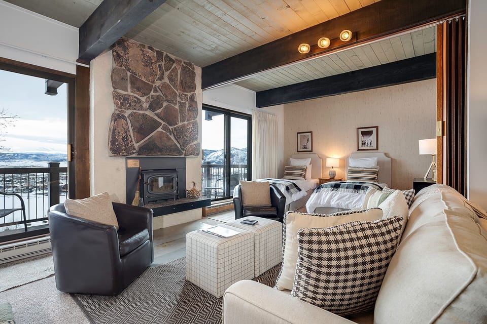 Cozy up by your stone fireplace while mountain views frame your alpine retreat through floor-to-ceiling windows.