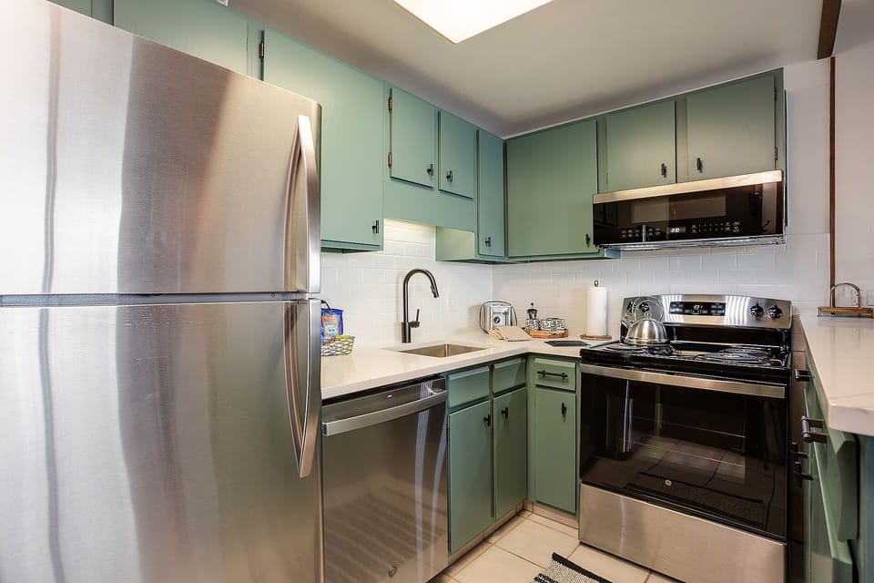 Your fully equipped kitchen features sage green cabinets, stainless steel appliances, and everything you need to prepare delicious meals during your stay.
