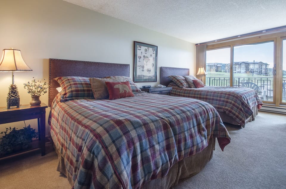 Sink into cozy plaid bedding while enjoying city views from your spacious bedroom, complete with warm lighting and thoughtful touches.