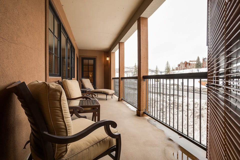 Relax on your private covered balcony with plush seating while enjoying peaceful winter mountain views.