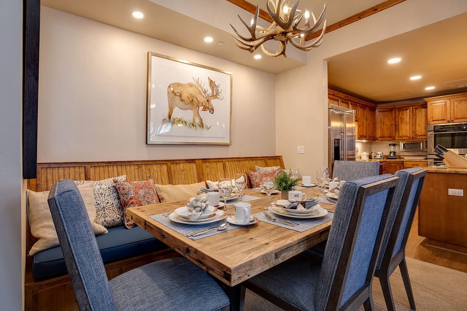 Gather around your elegant dining space where rustic charm meets refined comfort. The antler chandelier and cozy banquette create perfect moments for memorable meals together.