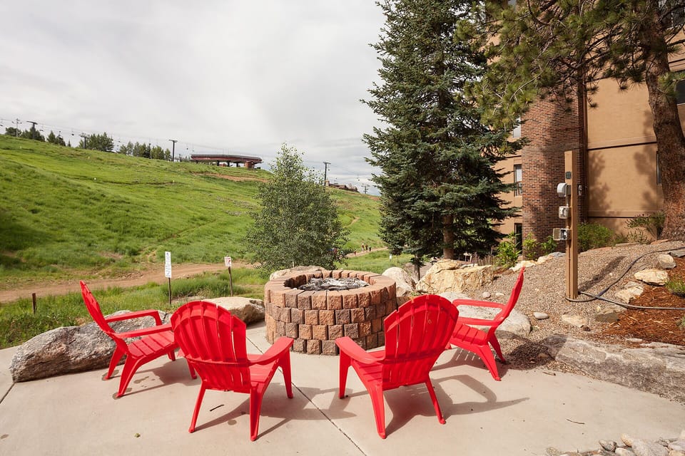 Gather around the stone firepit in vibrant red Adirondack chairs, where hillside views and mountain breezes set the scene for unforgettable evenings under the open sky.