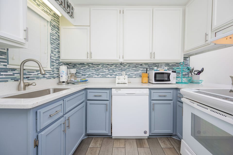 This kitchen features stylish blue cabinetry, essential appliances, and a sleek countertop, perfect for cooking and entertaining