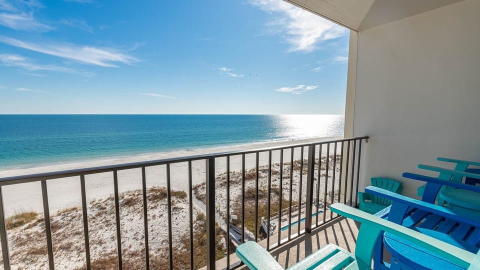 Enjoy stunning beachfront views from this inviting balcony with colorful seating, perfect for relaxation and sunsets