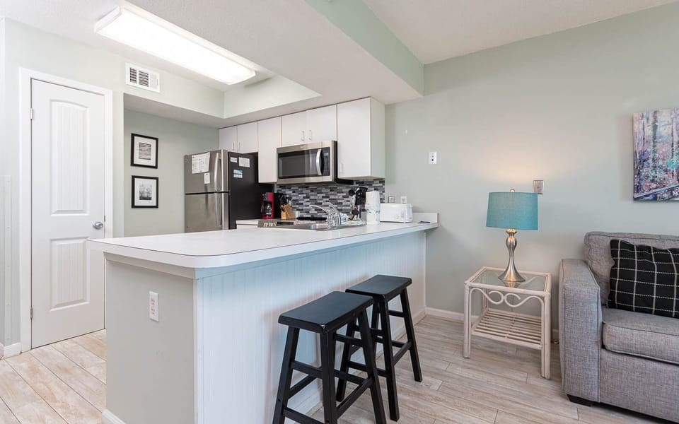 This kitchen features sleek stainless appliances, a stylish backsplash, and a cozy seating area for relaxed gatherings