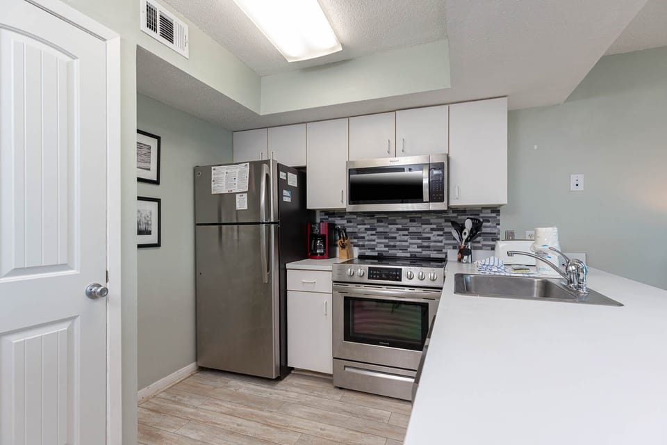 This modern kitchen features stainless steel appliances, sleek cabinetry, and a convenient layout for meal preparation