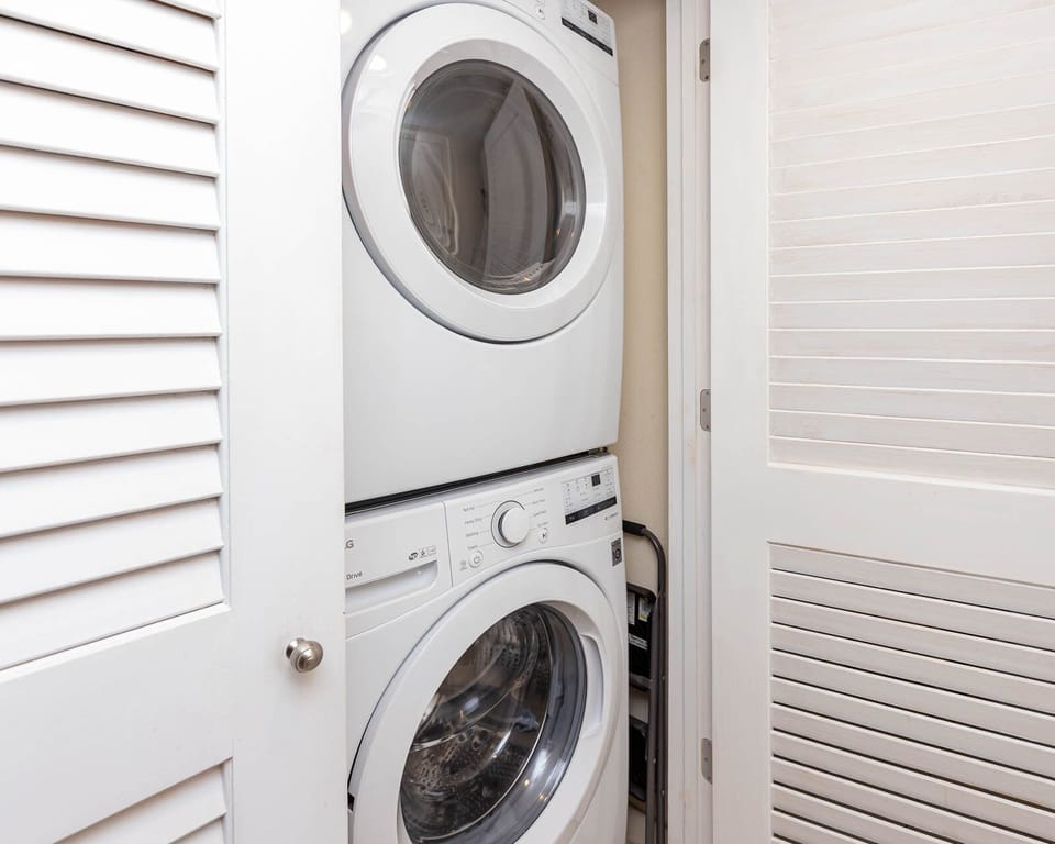 This laundry area features a stacked washer and dryer behind a stylish louvered door for your convenience