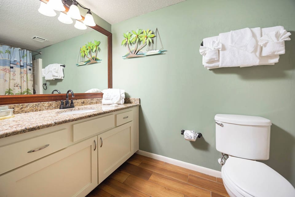 This guest bath features a spacious vanity with a granite countertop, decorative accents, and fresh towels