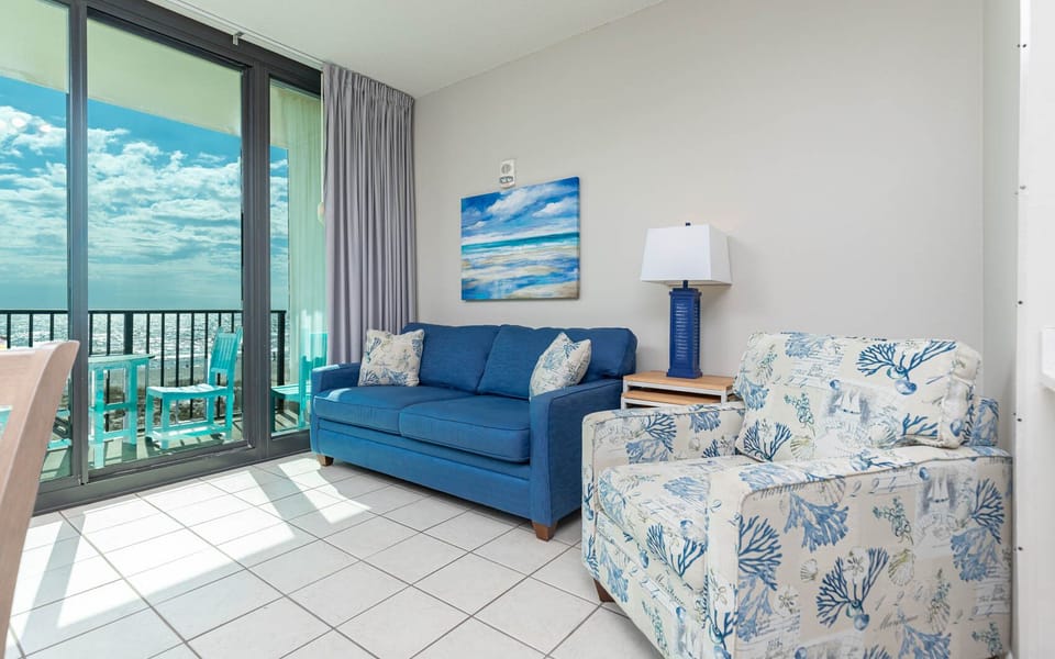 Relax on the blue sofa and enjoy the coastal artwork while natural light fills the inviting living space