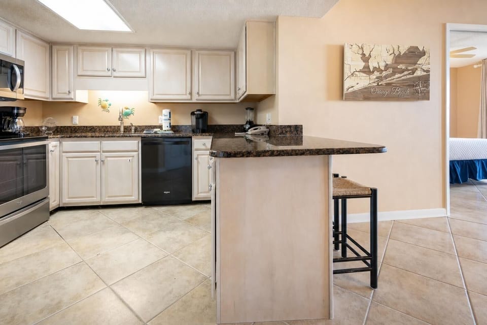 Modern kitchen features light cabinetry, granite countertops, Keurig and coffee maker, and a breakfast bar with seating